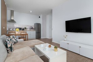 Ein modernes Wohnzimmer mit einer Couch, einem Couchtisch und einem an der Wand befestigten Flachbildfernseher.