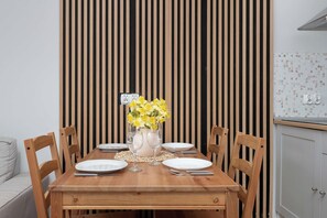 A dining table with four chairs, a vase with yellow flowers, and a white plate on the table. - Łódź | Karola Borowieckiego 1 | Spacious Apartment | Terrace (Łódź)