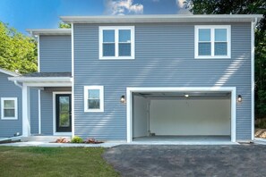 A two-story residential building with a garage, a front door, and a small front yard. - Fox Lake Extended-Stay Furnished 30-Day+ Suite (Fox Lake)