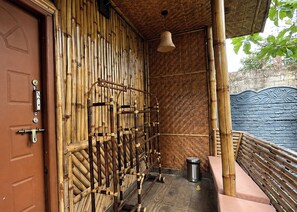 Una habitación con pared de bambú, un banco de madera y una lámpara colgante.