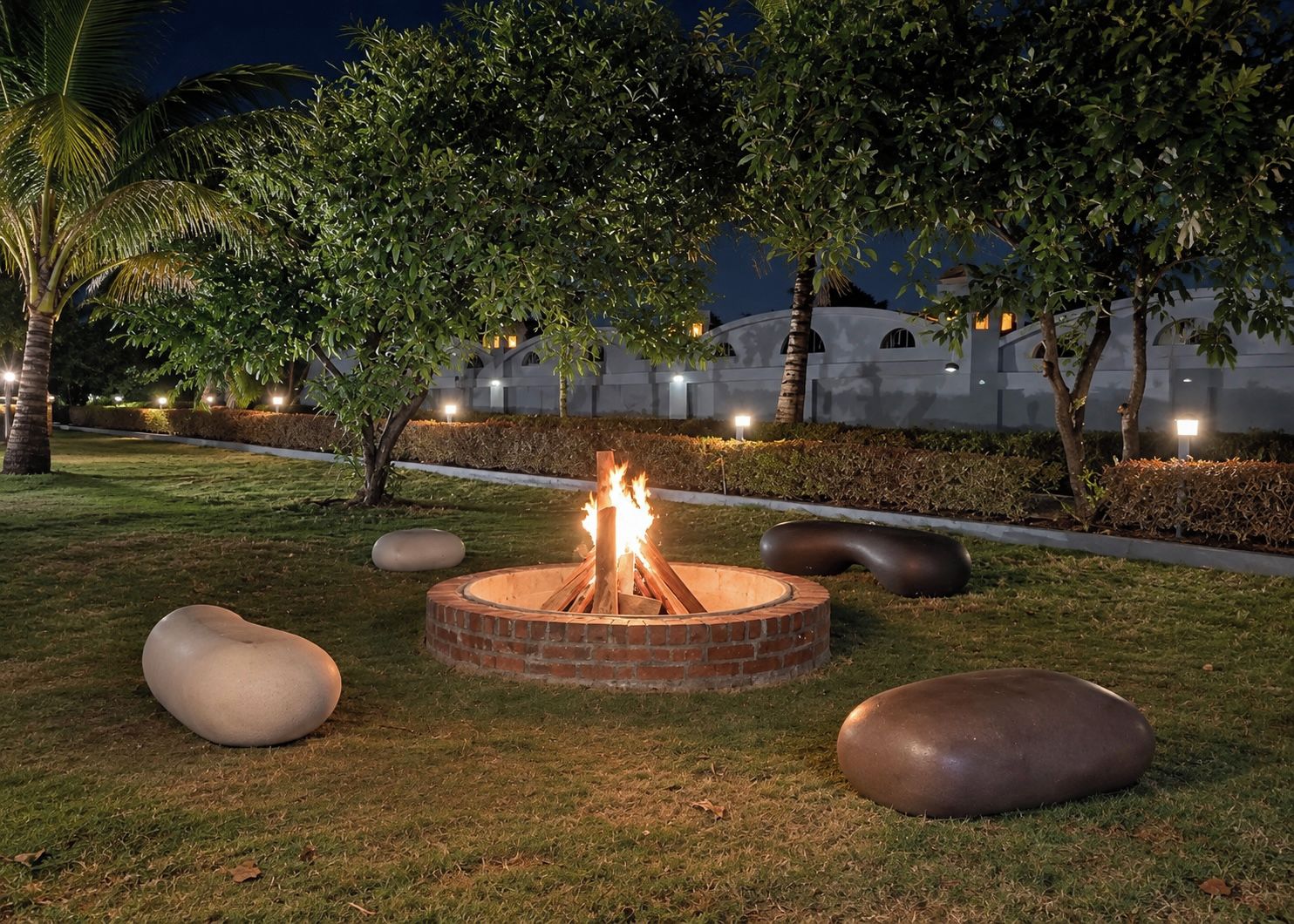 A circular fire pit with flames, surrounded by grass and large spherical stones.