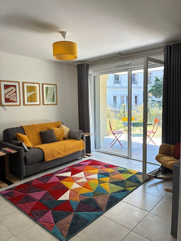 A modern living room with a sofa, a colorful geometric rug, and a view of the outside. - Les Pics Alpins (Saint Gervais)