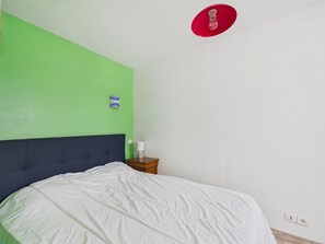 A room with a bed, a nightstand, a wall clock, and a red light fixture. - 7-person house near beach, garden & veranda (Saint-Jean-de-Monts)