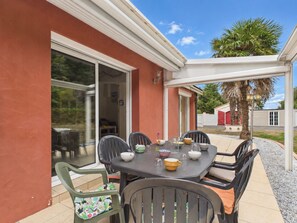 Eine Terrasse mit Tisch und Stühlen, eine Schiebetür und eine Palme im Hintergrund.