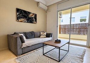 A modern living room with a grey sofa, a coffee table, and a patterned rug. - The Quiet Corner (Tunis)