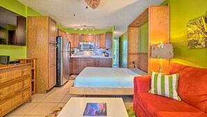 A compact living space with a kitchenette, a bed, a red sofa, and a dining area. - AVAILABLE IRONMAN 2026 - OCEANVIEW Brilliant condo Close to the PIER For Ironman (Kailua-Kona)