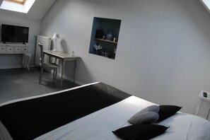 A room with a bed, a desk, a chair, a radiator, and a shelf with decorative items. - Logement avec 3 suites parentales,proche Mémorial de Vimy, Lens, Liévin, Arras (Givenchy-en-Gohelle)