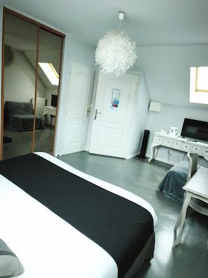 Un dormitorio con cama, cómoda, escritorio, silla, televisor y puerta con espejo.