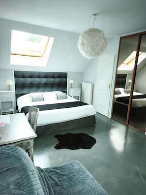 Un dormitorio moderno con una cama grande, mesitas de noche, un escritorio y un espejo.