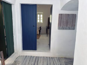 A hallway with a blue door, a rug, and a patterned wall hanging.