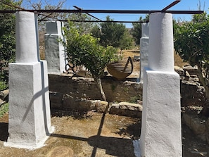 A stone structure with white pillars, a rustic stone wall, and a potted plant.