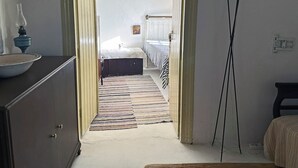 Ein Flur, der in ein Schlafzimmer mit Bett, Nachttisch und Lampe führt.