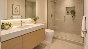 A modern bathroom with a glass-enclosed shower, a white sink, and a toilet. - Unionmark Suites (Toronto)