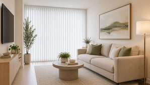 A modern living room with a beige sofa, a round coffee table, and a flat-screen TV mounted on the wall. - Unionmark Suites (Toronto)