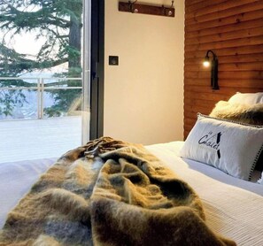 A bedroom with a bed, a window, and a wooden wall. - Chalet with hot tub above the Champagne vineyards (Cormoyeux)