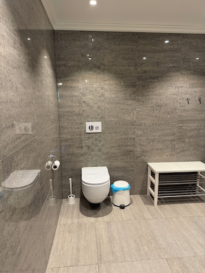 A modern bathroom with a toilet, bidet, and a small white table.
