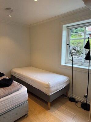 A small, single-bed room with a window, a bedside table, and a lamp. - Luxury 2-bedroom apartment in charming Vestland perfect for relaxing stay (Vestland)