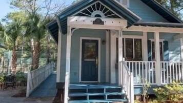 A two-story house with a porch and a staircase leading to the front door.