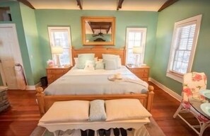 Ein Schlafzimmer mit einem großen Bett, einem Nachttisch, einem Sessel und einem Fenster.