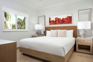 Une chambre moderne avec un grand lit, deux tables de chevet, une fenêtre offrant une belle vue et une œuvre d’art accrochée au mur.
