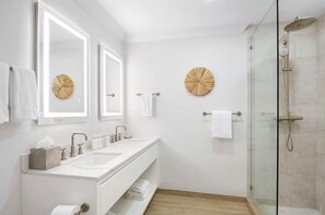 Un bagno moderno con due lavandini, cabina doccia in vetro e specchi decorativi a parete.