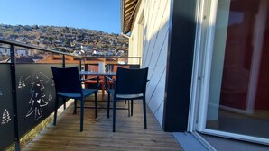 Un balcon avec un plancher en bois, deux chaises et une table.