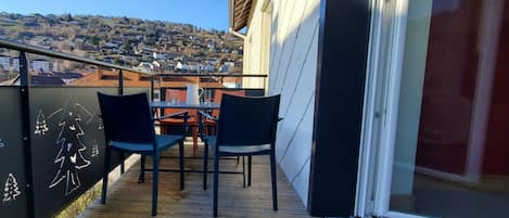 A balcony with a wooden floor, two chairs, and a table.
