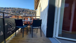 En balkon med trægulv, to stole og et bord.