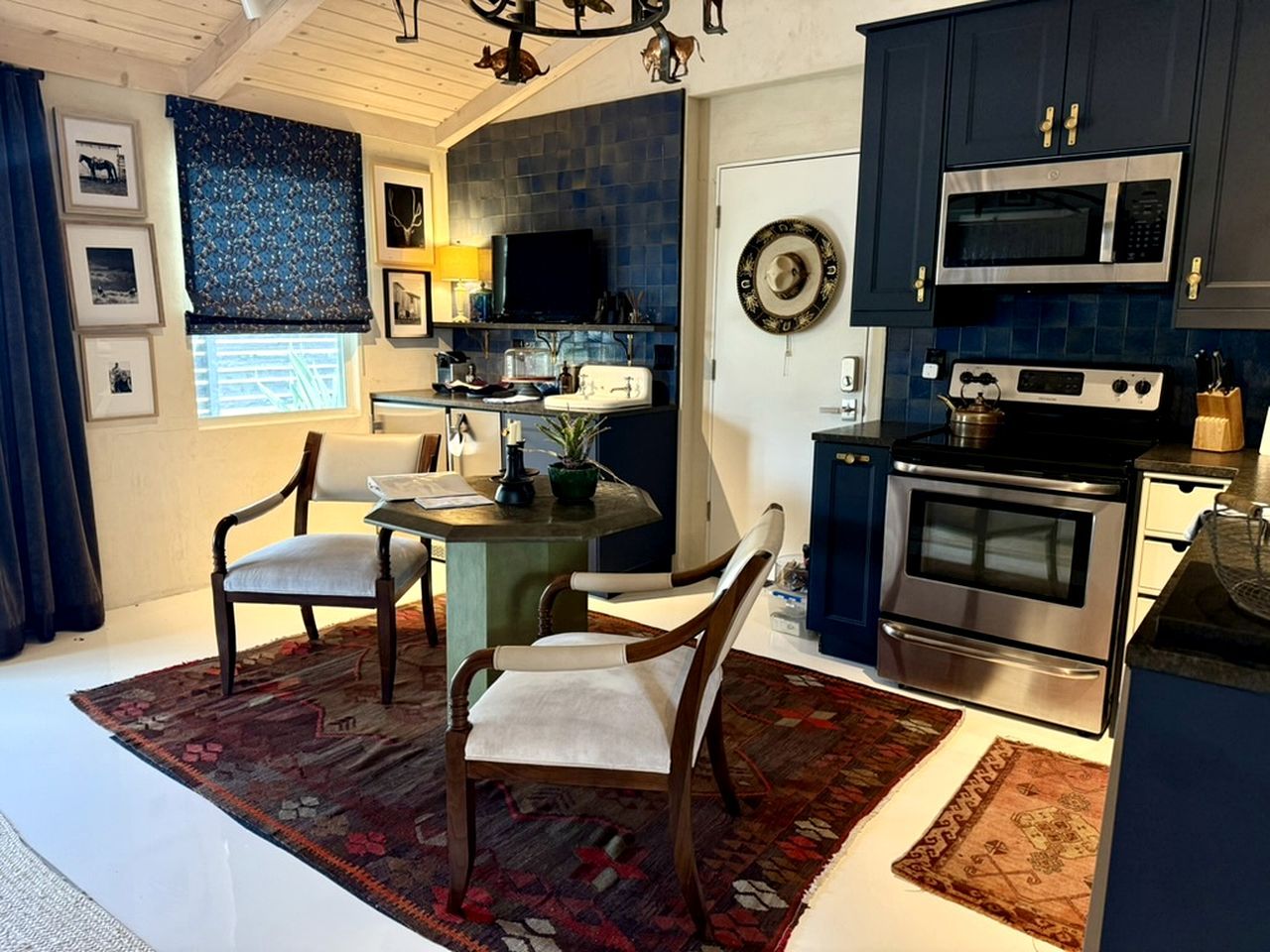 A modern kitchen with dark cabinetry, a microwave, stove, and a dining area with a table and chairs.