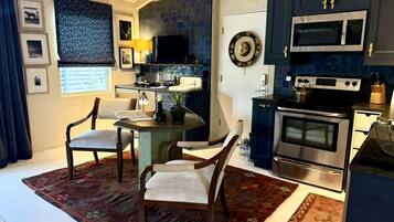 A modern kitchen with dark cabinetry, a microwave, stove, and a dining area with a table and chairs.