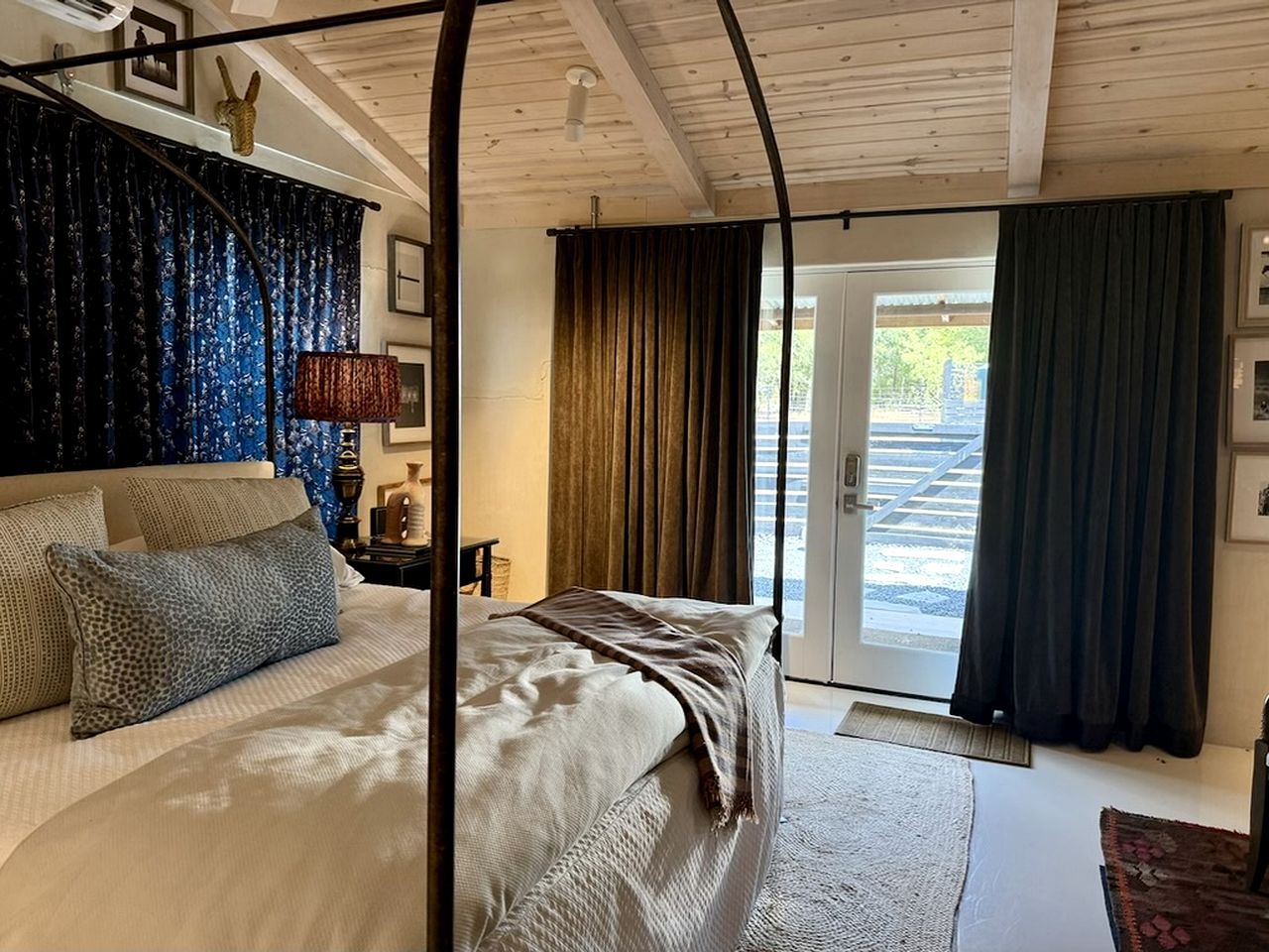 Una camera da letto con un letto grande, una finestra con tende e una porta che dà sull'esterno.