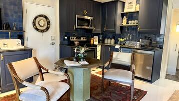 A compact kitchen with dark cabinets, a central island, and two chairs.