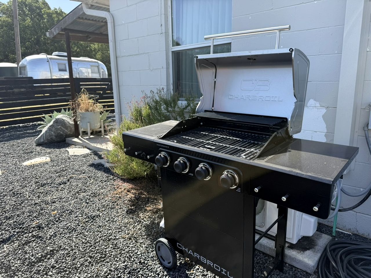 A portable charcoal grill with a control panel, positioned outdoors on a gravel surface.