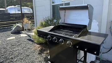A portable charcoal grill with a control panel, positioned outdoors on a gravel surface.