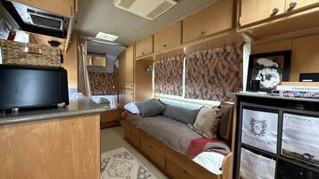Interior d'una caravana compacta amb cuineta, sofà llit i nevera petita.