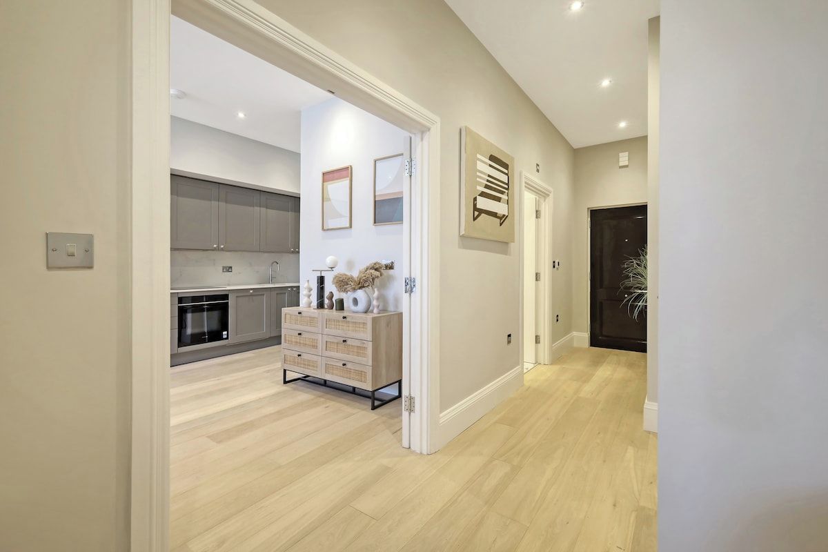A modern kitchen with grey cabinets, a wooden cabinet with drawers, and a white countertop.