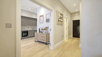 A modern kitchen with grey cabinets, a wooden cabinet with drawers, and a white countertop.
