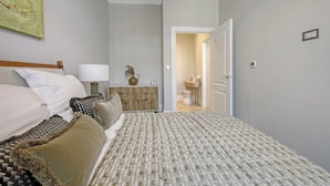 A bedroom with a bed, bedside table, lamp, and a door leading to a bathroom. - Luxury Apartment w/ Modern Kitchen & Free Parking (Southend-on-Sea)
