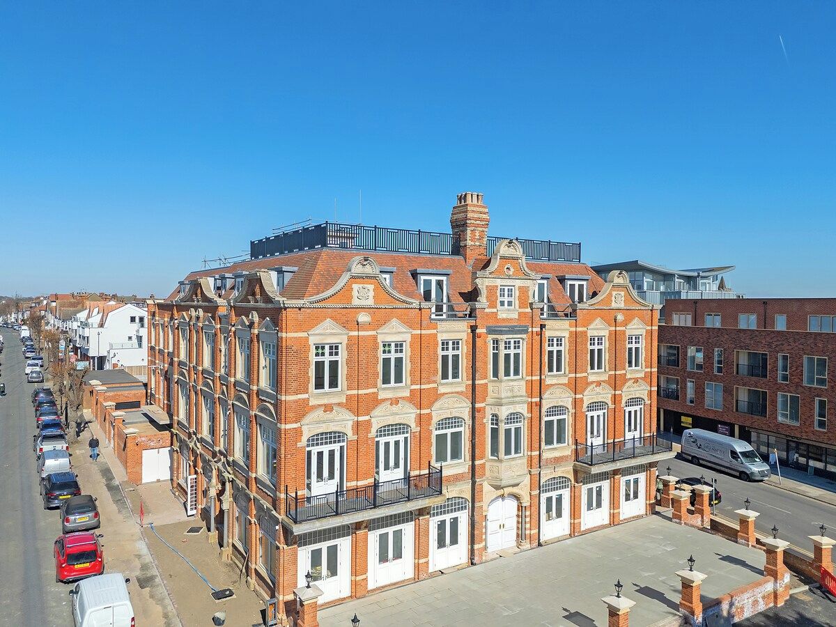A multi-story red brick building with a central courtyard, large windows, and a flat roof.