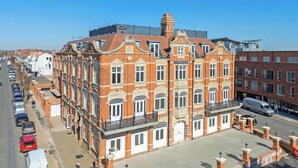 A multi-story red brick building with a central courtyard, large windows, and a flat roof. - Luxury Apartment w/ Modern Kitchen & Free Parking (Southend-on-Sea)