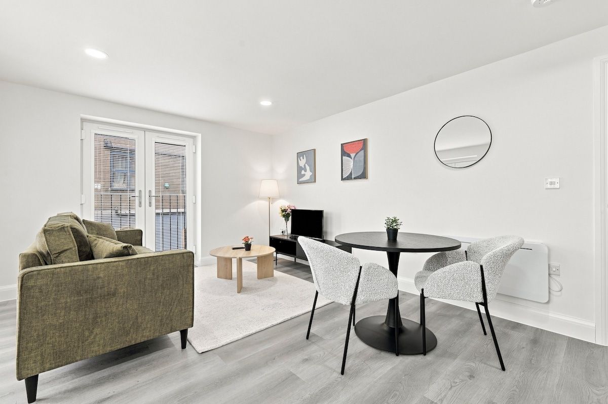 Un salon moderne avec un canapé, une table à manger et des chaises, un téléviseur et des œuvres d’art accrochées au mur.