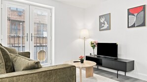 A modern living room with a sofa, a coffee table, a TV, and artwork on the wall.