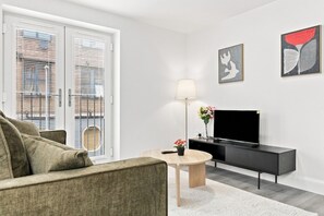 A modern living room with a sofa, a coffee table, a TV, and artwork on the wall.