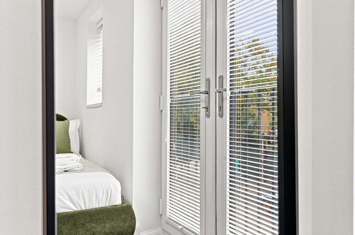Ein Schlafzimmer mit einem Bett, einem grünen Sessel und einem Fenster mit Jalousien.