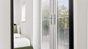Ein Schlafzimmer mit einem Bett, einem grünen Sessel und einem Fenster mit Jalousien.