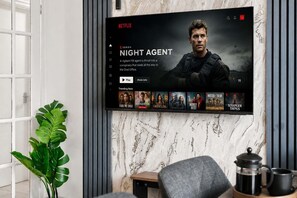 A television mounted on a wall displaying the Netflix series 'Night Agent' with a selection of other series available. - Entire 5 Bed house in Manchester, UK (Withington)
