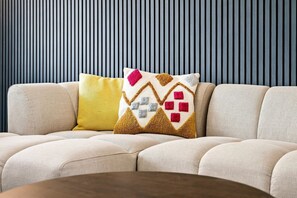 A sofa with a patterned cushion and a plain cushion against a striped wall. - Entire 5 Bed house in Manchester, UK (Withington)