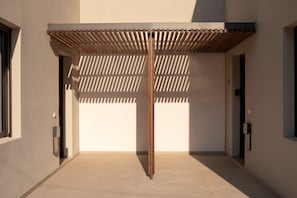 Un edificio moderno con una columna central, una estructura de madera con listones en la parte superior y un frente sencillo.