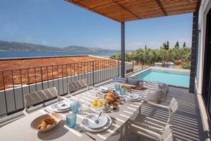 Una terraza con una mesa para dos, con vista a una piscina y al mar.