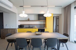 A modern kitchen with a large dining table, chairs, and pendant lighting.
